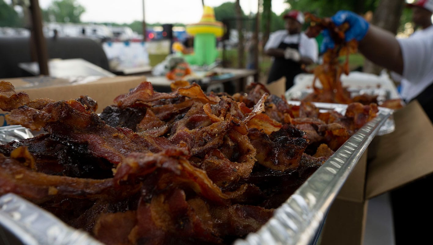 A close-up of several chafing dishes filled with bacon.