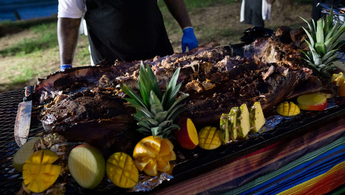 A large slab of ready-to-serve bar-b-que adorned with fruit.